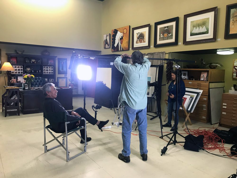 A small white dog in a stroller outside a clothing store.