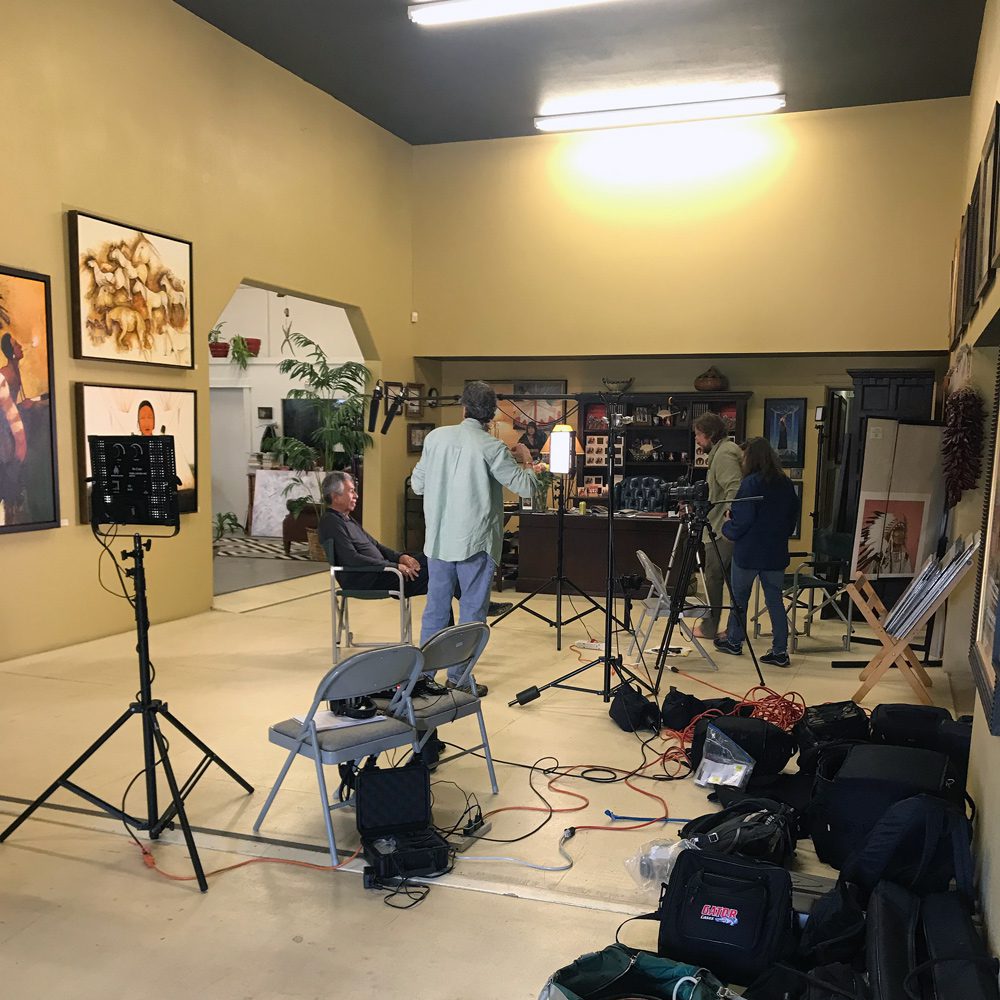 A small white dog in a stroller outside a clothing store.