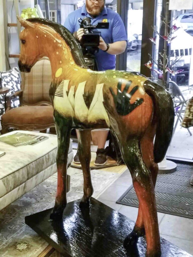 A small white dog in a stroller outside a clothing store.