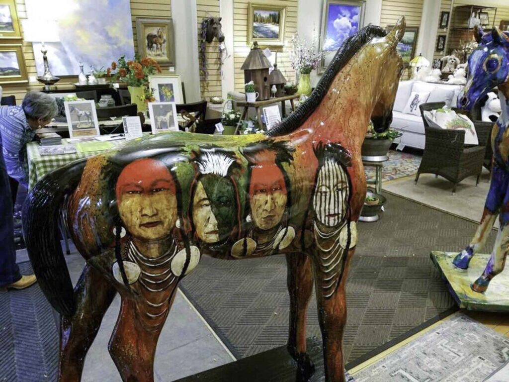 A small white dog in a stroller outside a clothing store.