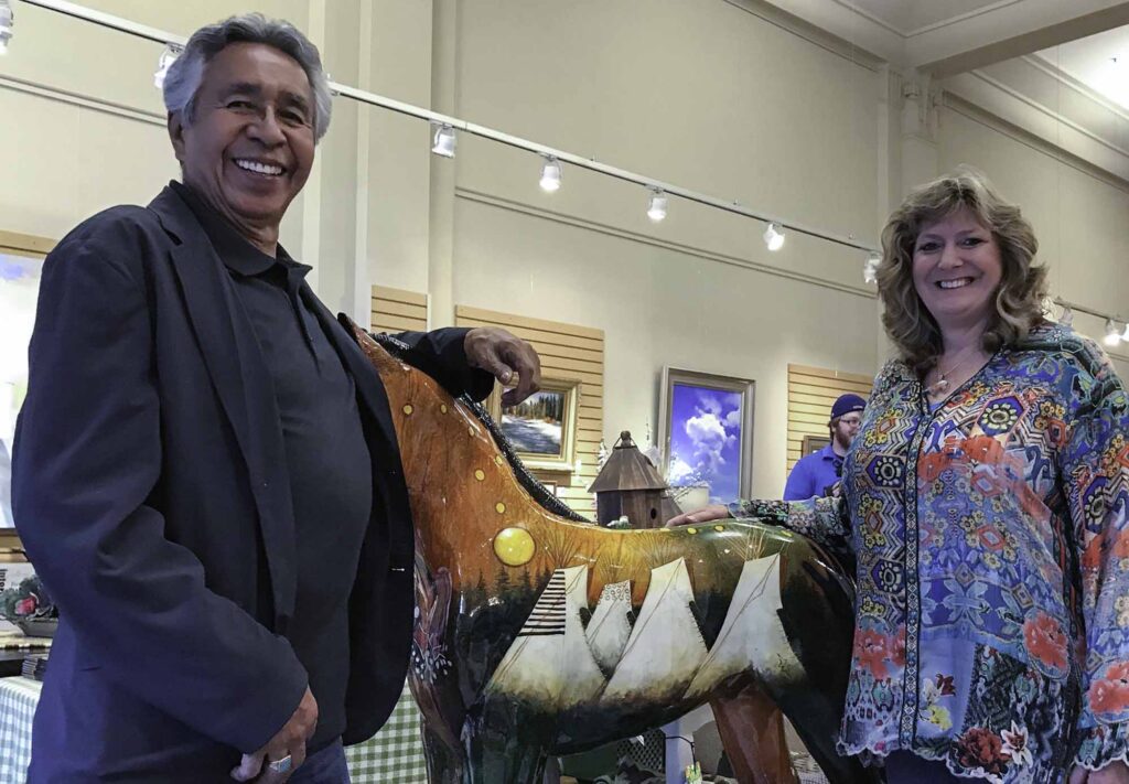A small white dog in a stroller outside a clothing store.