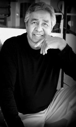 A small white dog in a stroller outside a clothing store.