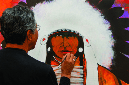 Painter working on indigenous-themed canvas