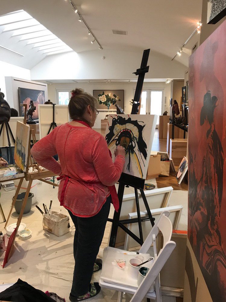 A small white dog in a stroller outside a clothing store.