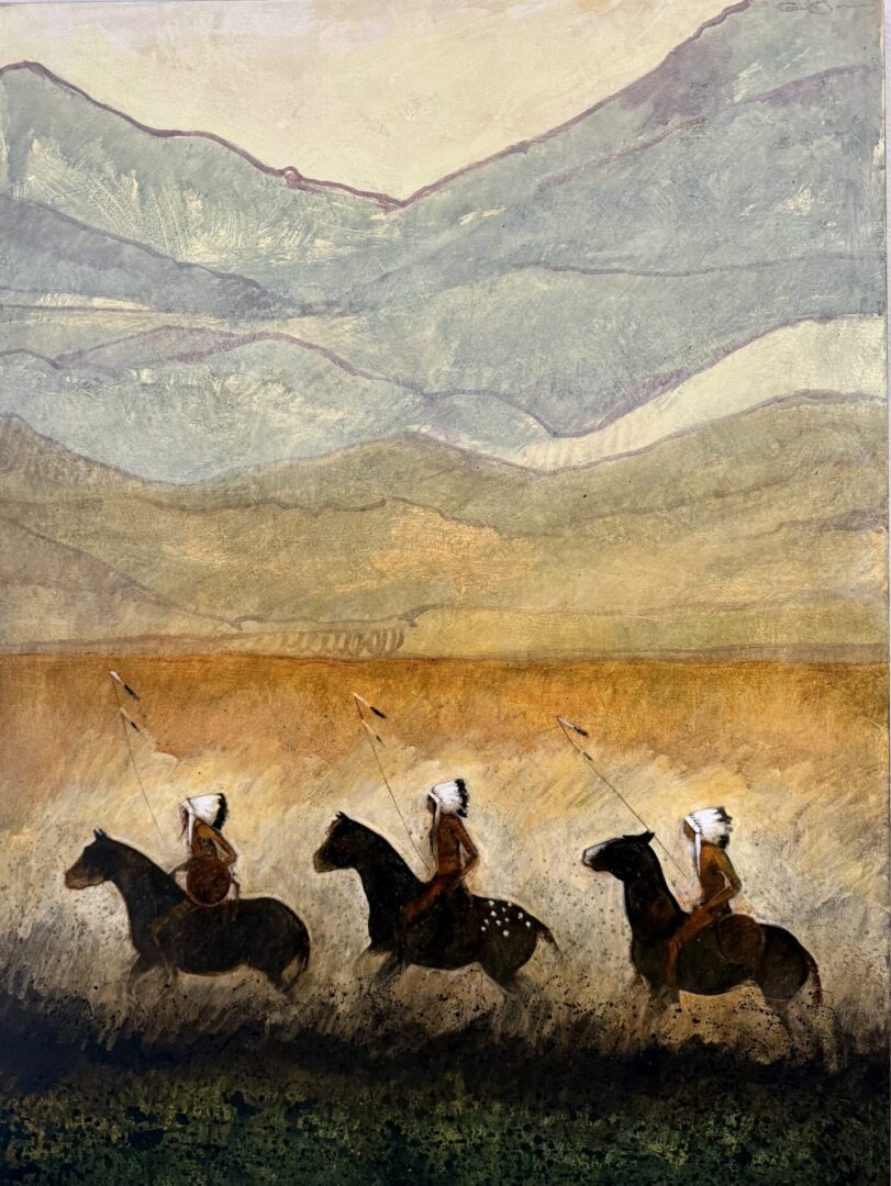 Three Native American riders on horses against a mountainous backdrop.