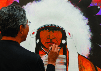 Painter working on indigenous-themed canvas